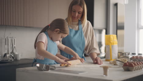 homemade-bakery-woman-and-child-are-cooking-together-in-kitchen-girl-is-rolling-out-dough